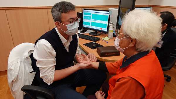 孫茂雄醫師為高齡九十二歲的陳奶奶把脈看診。（卓冠伶攝）