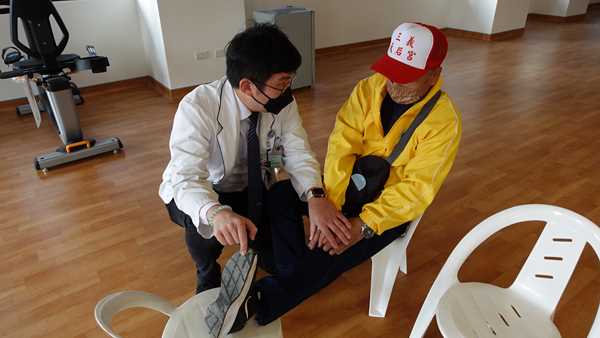 物理治療師陳義豪（左）針對每一位長輩症狀不同，指導復健方式。（卓冠伶攝）